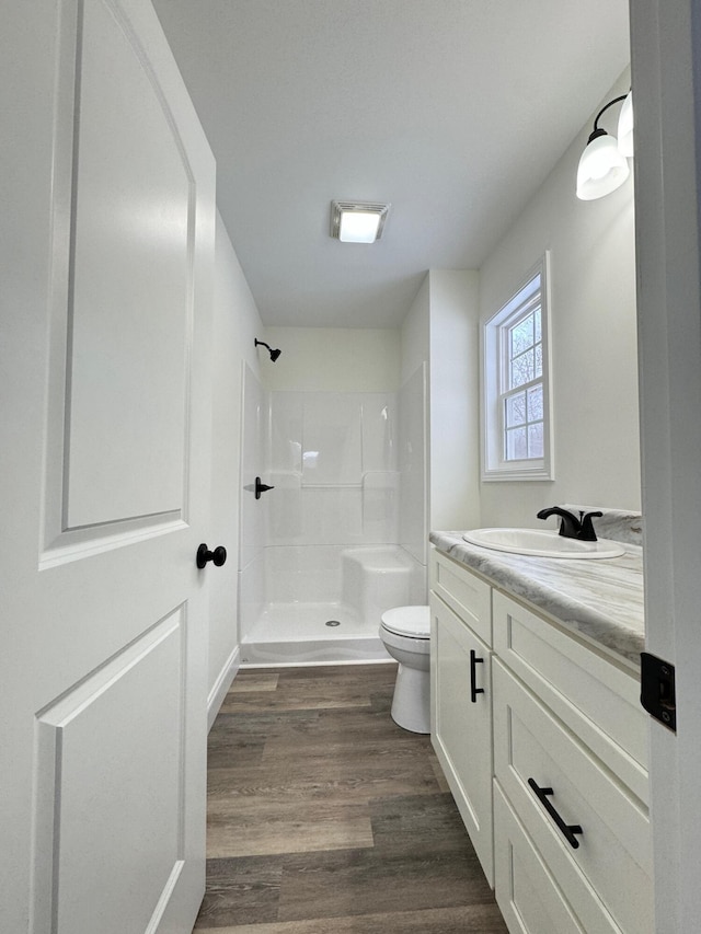 bathroom featuring a shower, hardwood / wood-style floors, vanity, and toilet