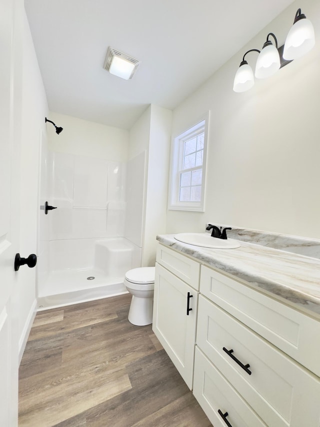 bathroom with a shower, vanity, hardwood / wood-style flooring, and toilet