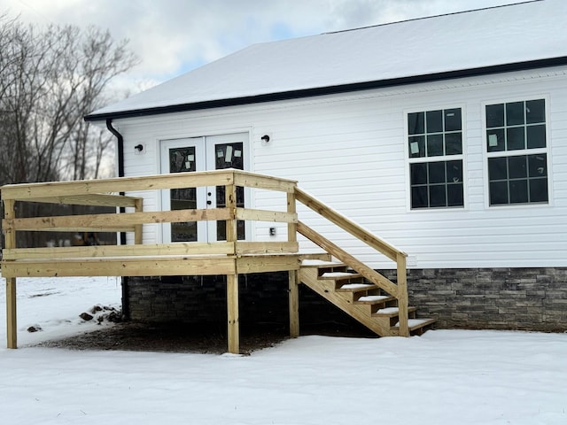 snow covered property entrance featuring a deck