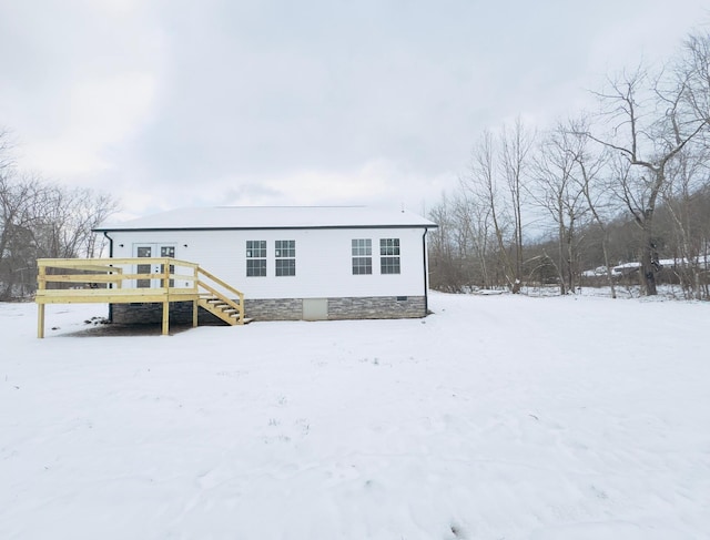 snow covered back of property featuring a deck