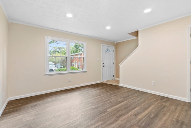 entrance foyer with wood-type flooring, a textured ceiling, and ornamental molding