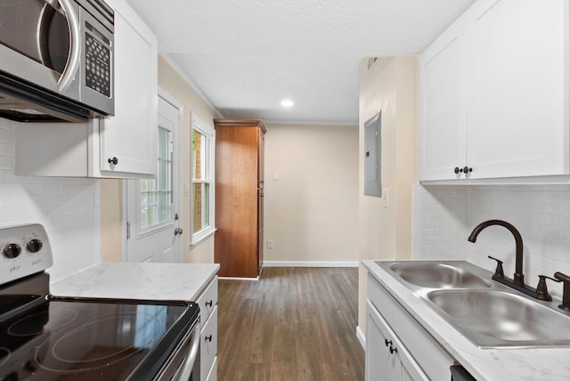 kitchen with appliances with stainless steel finishes, electric panel, white cabinetry, and sink