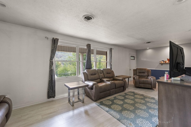 living room with a textured ceiling and light wood-type flooring