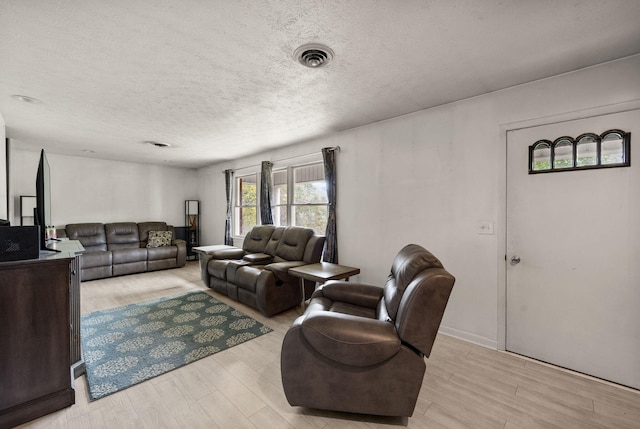 living room with a textured ceiling and light hardwood / wood-style flooring