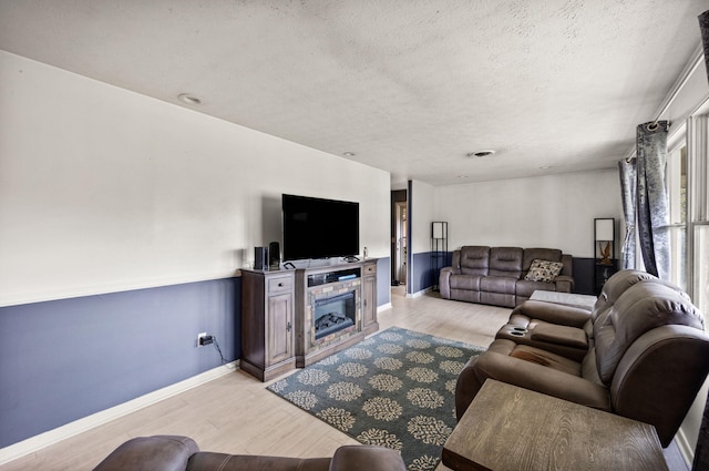 living room featuring light wood-type flooring and a textured ceiling