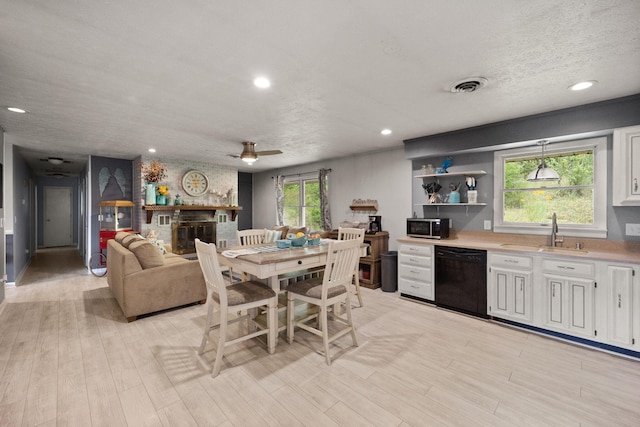 dining space featuring sink, ceiling fan, a brick fireplace, and a wealth of natural light