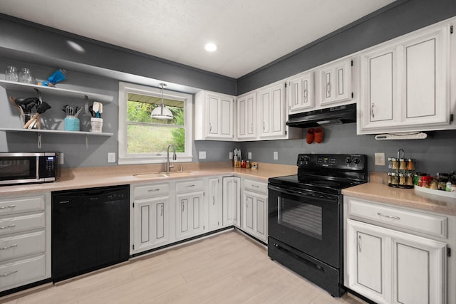 kitchen with sink, white cabinets, hanging light fixtures, light hardwood / wood-style flooring, and black appliances