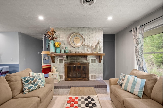 living room with light wood-type flooring, a textured ceiling, and a fireplace