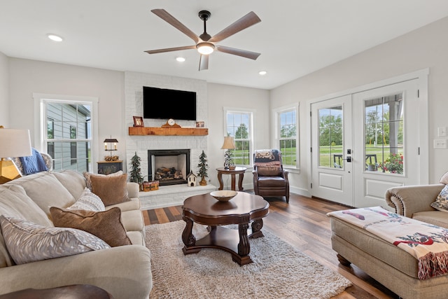 living room featuring a large fireplace, ceiling fan, hardwood / wood-style floors, and french doors