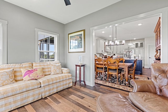 living room featuring ceiling fan with notable chandelier and light hardwood / wood-style flooring