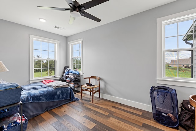 bedroom with multiple windows, ceiling fan, and dark wood-type flooring