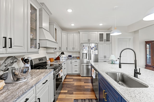 kitchen with pendant lighting, dark wood-type flooring, sink, blue cabinetry, and stainless steel appliances