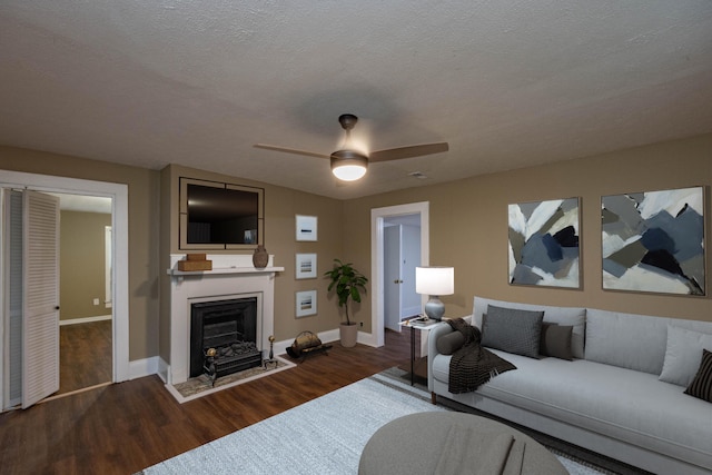 living room featuring ceiling fan, dark hardwood / wood-style flooring, and a textured ceiling