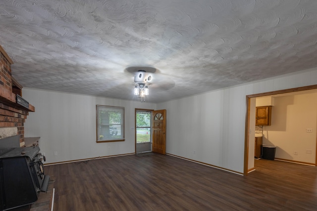 unfurnished living room featuring a textured ceiling, a wood stove, and dark wood-type flooring