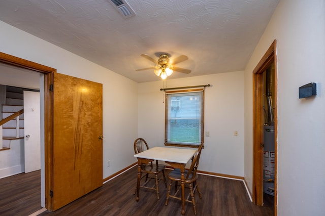 dining area featuring a textured ceiling, ceiling fan, dark wood-type flooring, and water heater