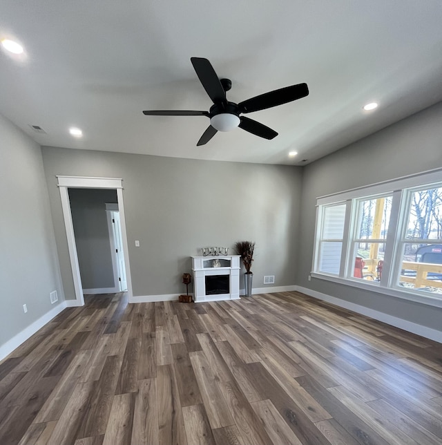 unfurnished living room featuring a fireplace, baseboards, and wood finished floors