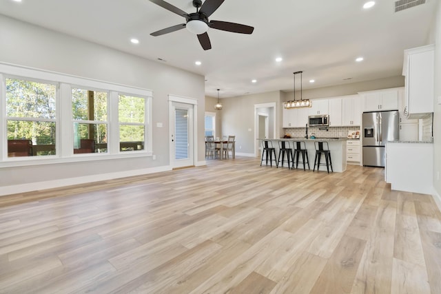 unfurnished living room featuring recessed lighting, a ceiling fan, baseboards, light wood-style floors, and visible vents