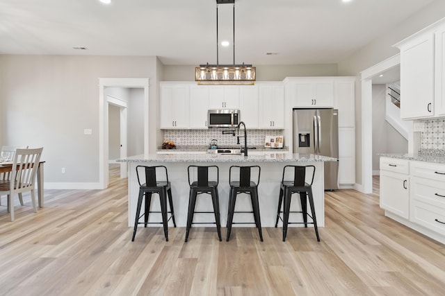 kitchen with light wood-type flooring, stainless steel appliances, and a kitchen breakfast bar