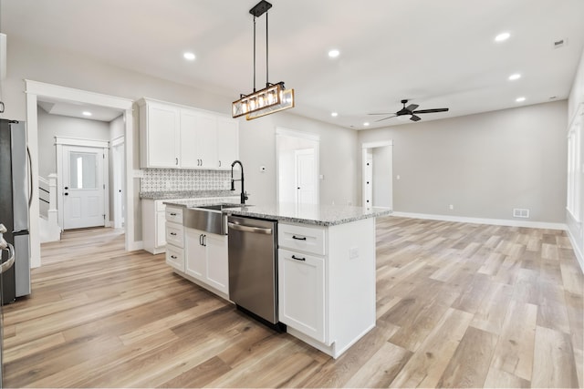 kitchen featuring backsplash, appliances with stainless steel finishes, light wood-style floors, a kitchen island with sink, and a sink