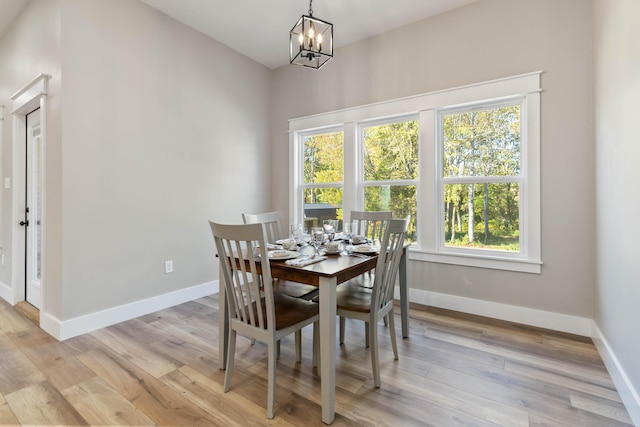 dining area with baseboards, a notable chandelier, and light wood finished floors