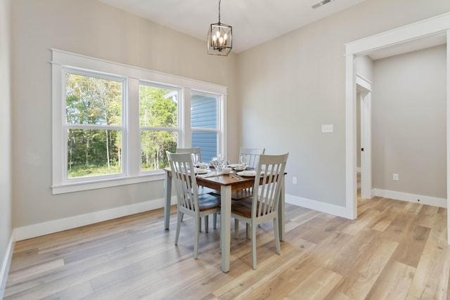 dining space with baseboards, a chandelier, visible vents, and light wood-style floors