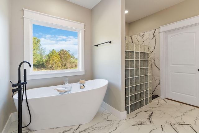 bathroom with a freestanding bath, marble finish floor, tiled shower, and baseboards