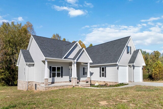 view of front of property featuring a garage, covered porch, and a front yard