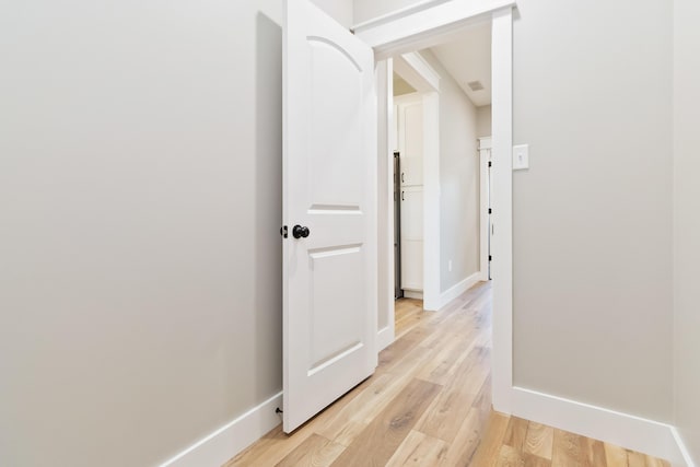 hallway featuring light wood-type flooring and baseboards