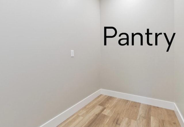 clothes washing area with light wood-style floors and baseboards