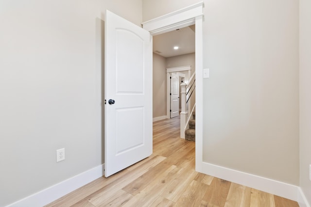 empty room featuring baseboards, stairs, and light wood-style floors