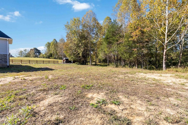 view of yard with fence and a rural view