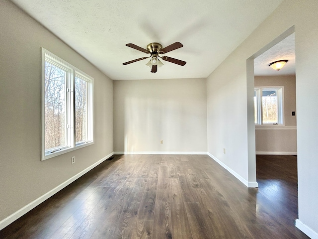 unfurnished room with ceiling fan, dark hardwood / wood-style flooring, and plenty of natural light