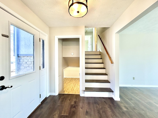 foyer with a textured ceiling, a healthy amount of sunlight, and dark hardwood / wood-style floors