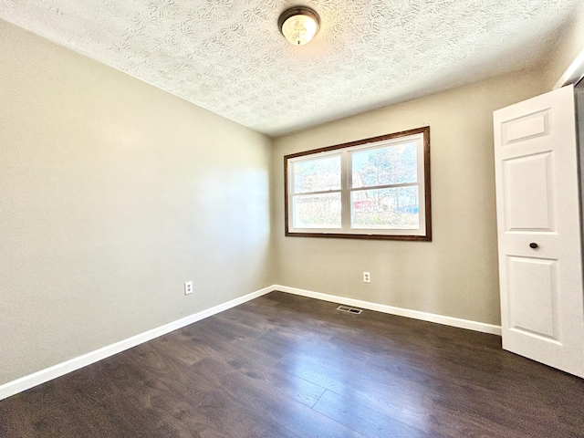 unfurnished room with dark wood-type flooring and a textured ceiling