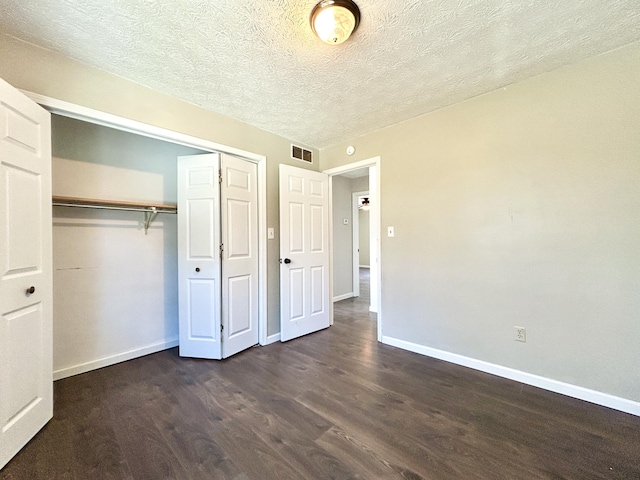 unfurnished bedroom featuring a textured ceiling, a closet, and dark hardwood / wood-style floors