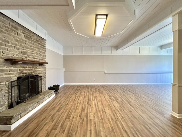 unfurnished living room featuring wooden ceiling, hardwood / wood-style floors, and a stone fireplace