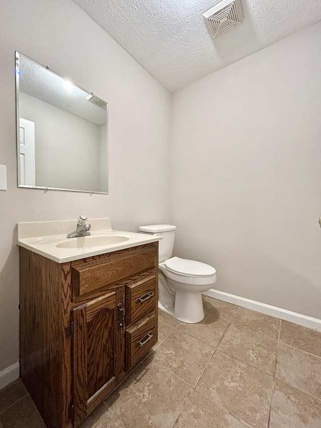 bathroom featuring a textured ceiling, vanity, and toilet