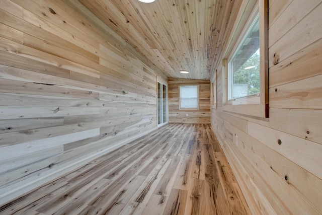 additional living space with light hardwood / wood-style flooring, wooden walls, and wooden ceiling