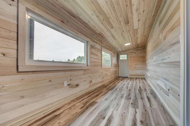 additional living space with light hardwood / wood-style floors, wood walls, lofted ceiling, and wood ceiling