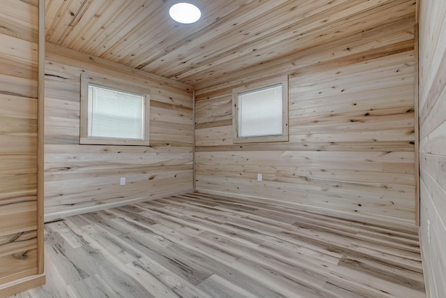 empty room with wooden walls, light wood-type flooring, and wooden ceiling