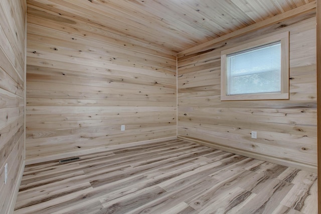 empty room featuring wooden ceiling, light hardwood / wood-style floors, and wood walls