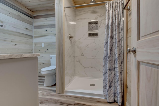 bathroom featuring toilet, a stall shower, wooden walls, and wood finished floors