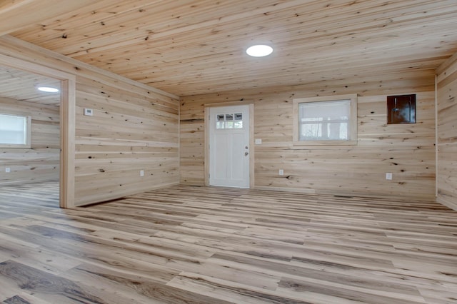 empty room featuring wood ceiling, light wood-type flooring, and wooden walls