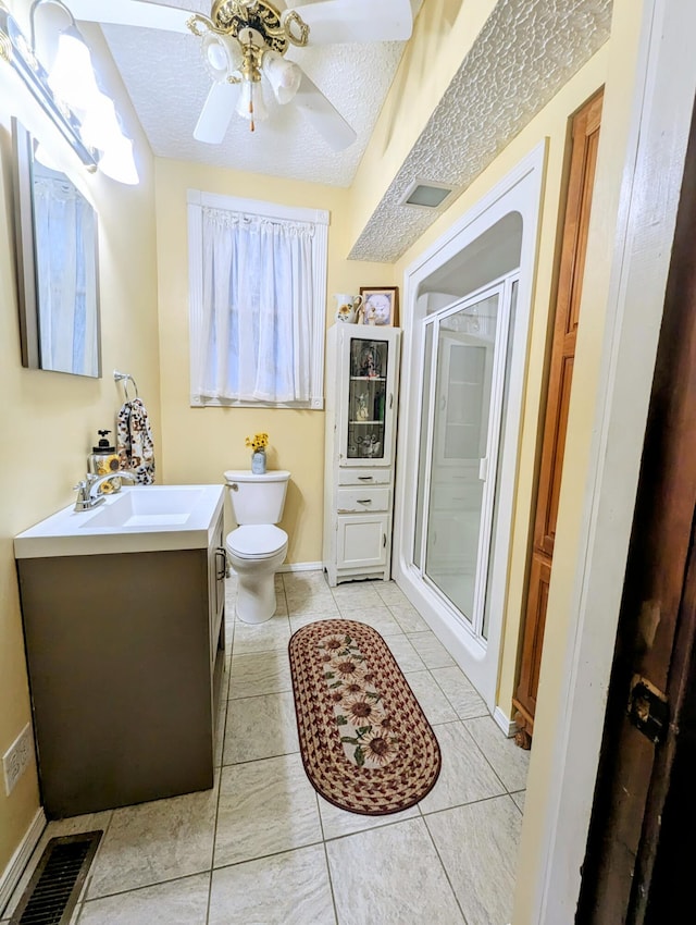 bathroom with tile patterned flooring, a shower with door, vanity, toilet, and ceiling fan