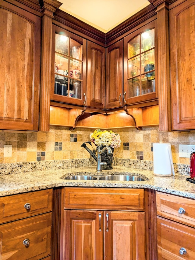 kitchen with decorative backsplash, sink, and light stone counters