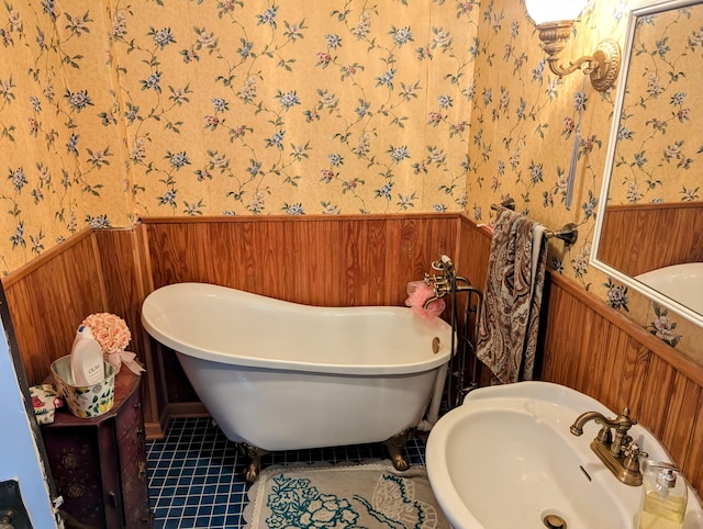 bathroom with a tub, sink, and tile patterned floors