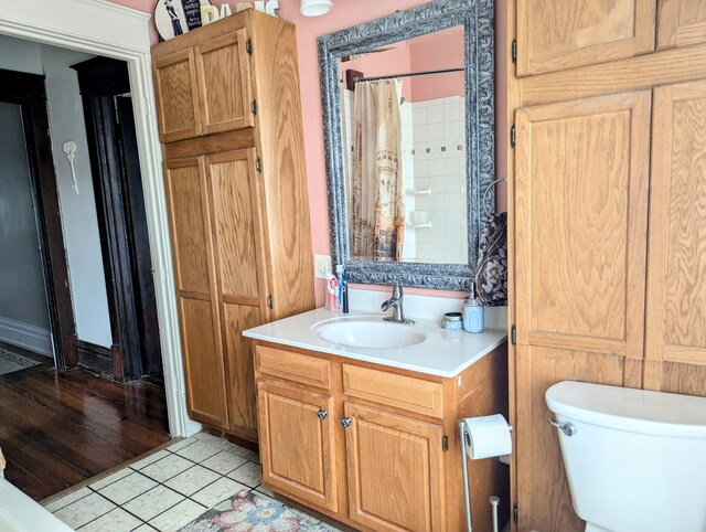 bathroom featuring toilet, tile patterned floors, vanity, and curtained shower