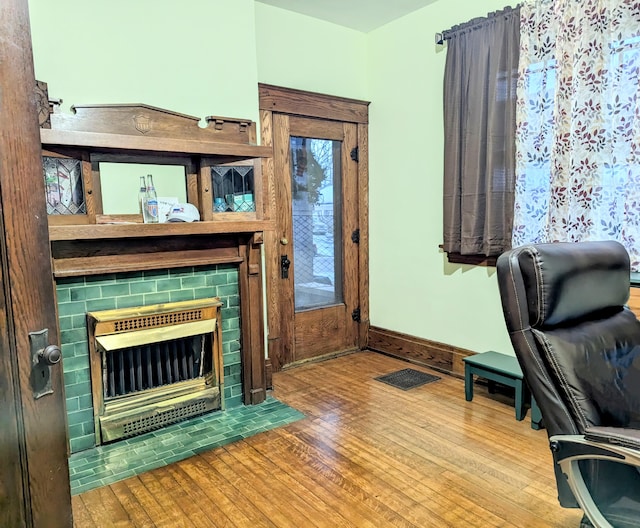 office area featuring a tile fireplace and light hardwood / wood-style floors