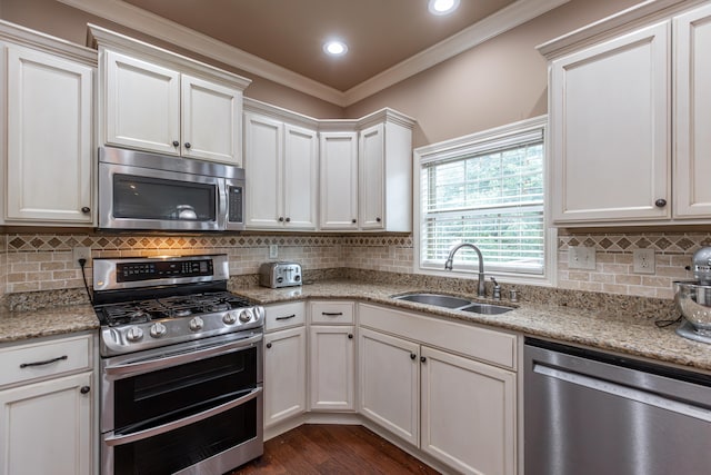 kitchen with stainless steel appliances, white cabinetry, crown molding, and sink