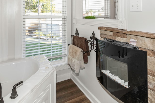 bathroom with hardwood / wood-style flooring, plenty of natural light, and a tub